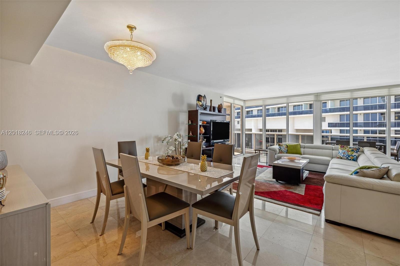 A dining area and living room with tile floors, a crystal chandelier, and floor-to-ceiling windows — 1800 S Ocean Dr # 1005, Hallandale Beach FL 33009, HALLANDALE BEACH, FL