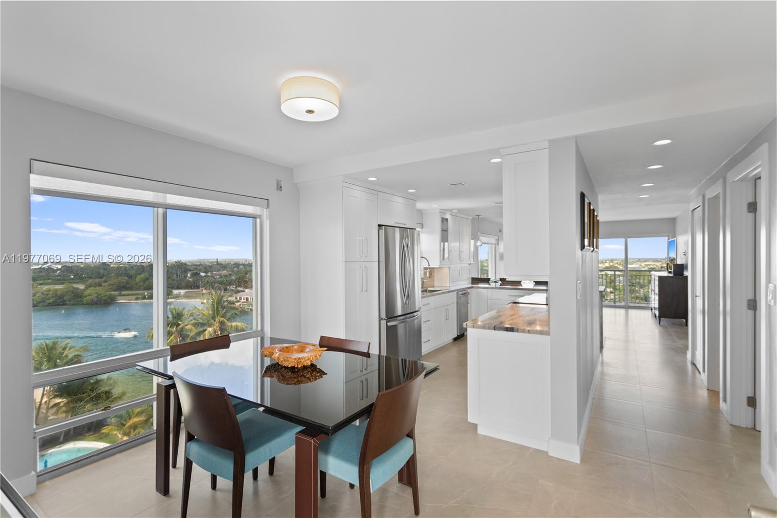 A dining area with a glass table overlooks a waterfront view next to a kitchen — 2611 N Riverside Dr # 901, Pompano Beach FL 33062, POMPANO BEACH, FL