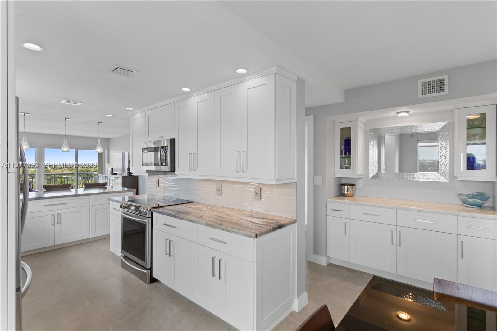 A modern kitchen features white cabinetry, stone countertops, and stainless steel appliances — 2611 N Riverside Dr # 901, Pompano Beach FL 33062, POMPANO BEACH, FL