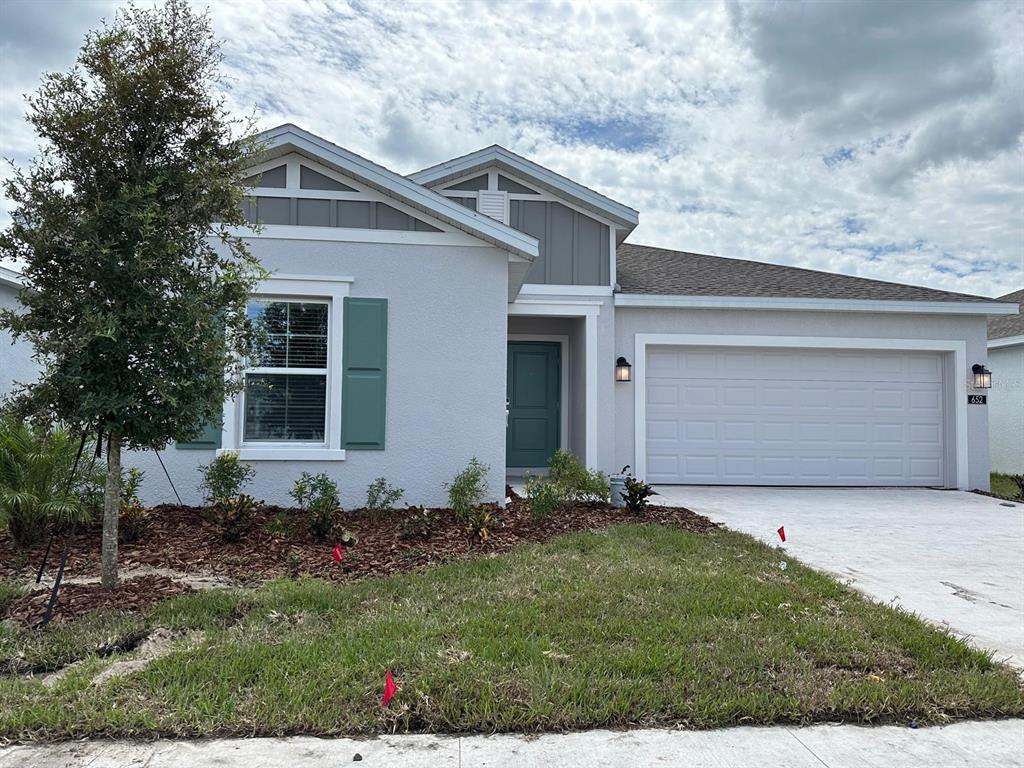 A single-story house with a light gray exterior, teal door, and a two-car garage — 652 TROTTERS DRIVE, EAGLE LAKE, FL