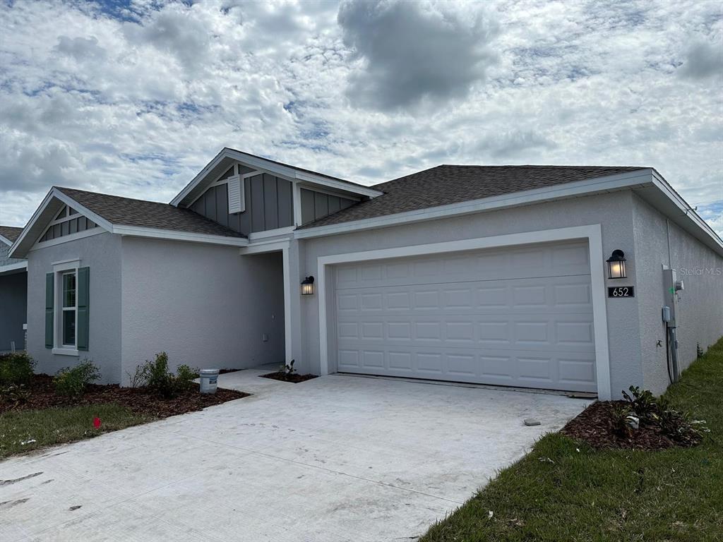 A single-story house with a light gray stucco exterior and a two-car garage — 652 TROTTERS DRIVE, EAGLE LAKE, FL