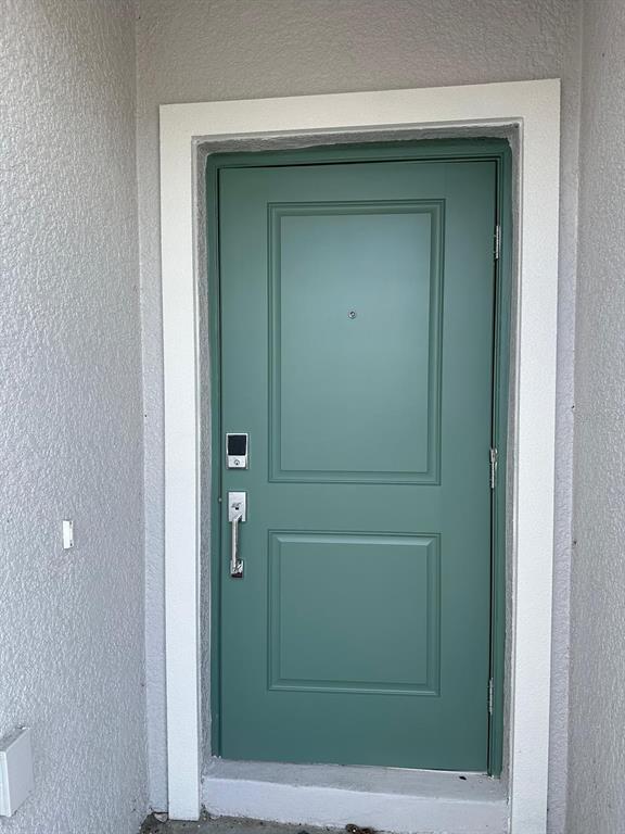 A green front door with a silver handle and smart lock set in a white frame — 652 TROTTERS DRIVE, EAGLE LAKE, FL