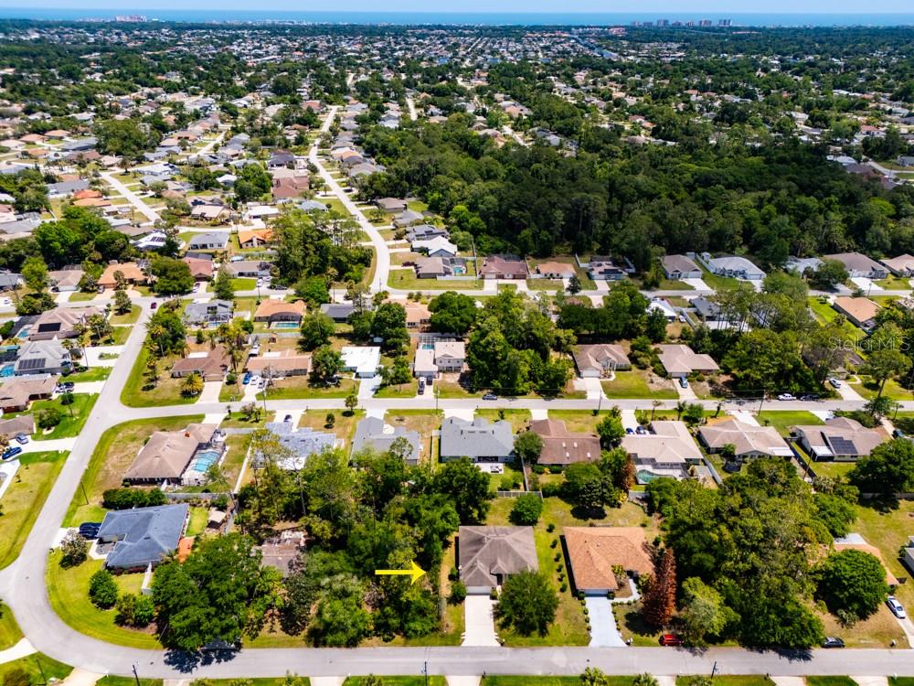 An aerial view of a suburban neighborhood with a yellow arrow pointing to a house — 35 FOXHALL LANE, PALM COAST, FL