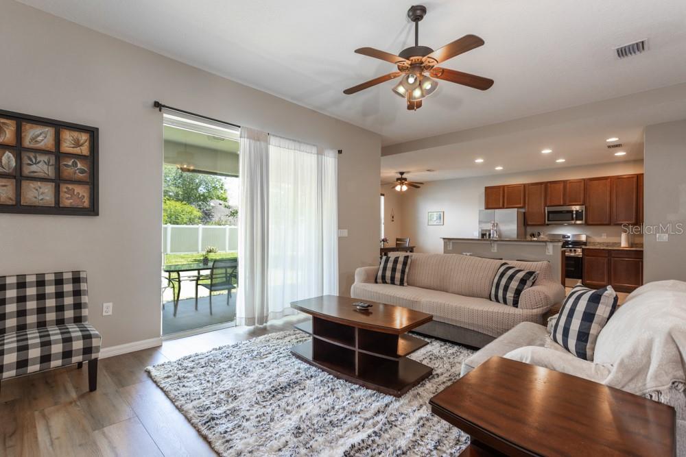 A living room with wood-look flooring, a shaggy rug, and an open kitchen beyond — 35 FOXHALL LANE, PALM COAST, FL