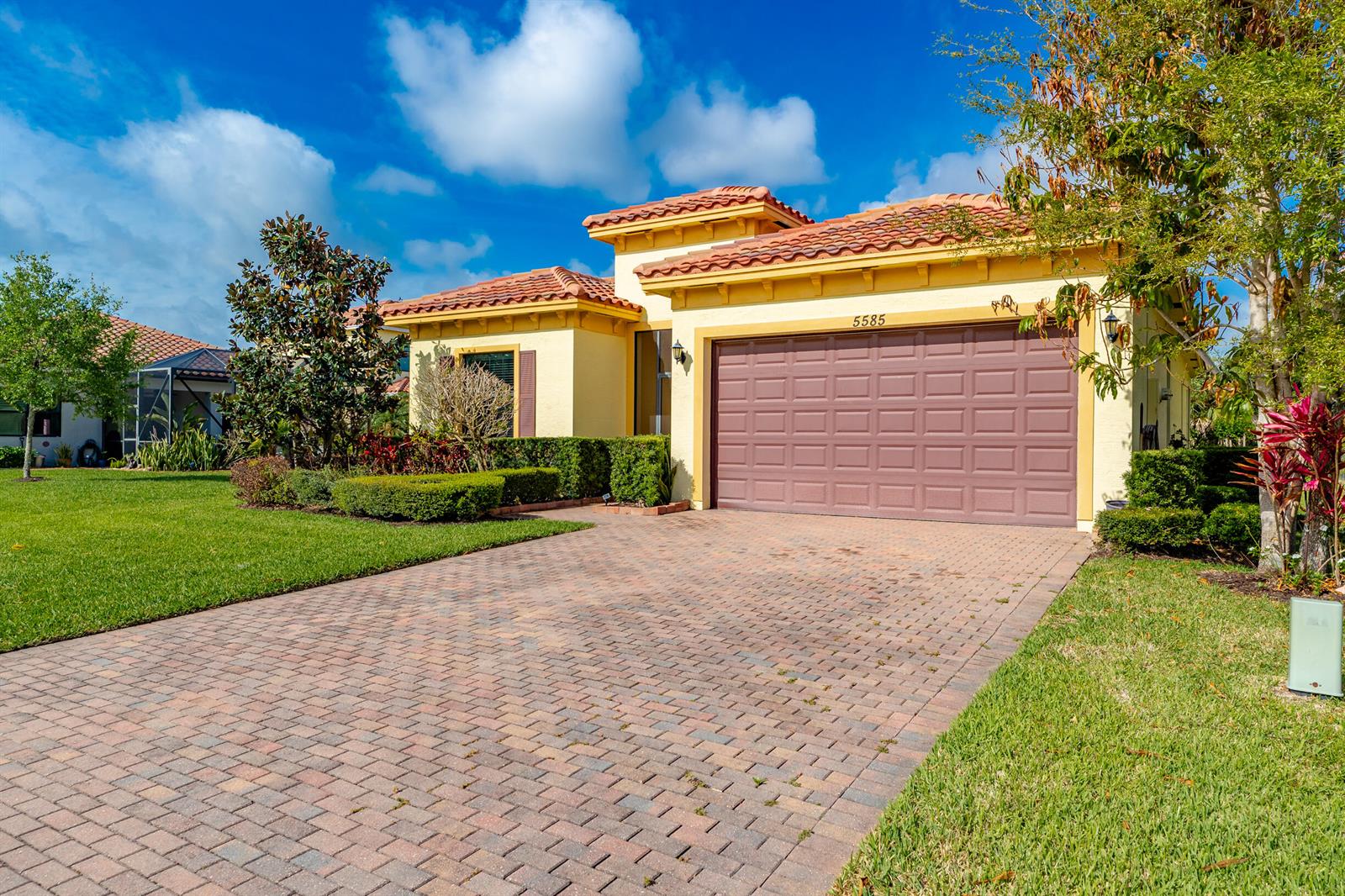 A single-story house with a terracotta tile roof, yellow stucco walls, and a brick driveway — 5585 40th Avenue, Vero Beach FL 32967, VERO BEACH, FL