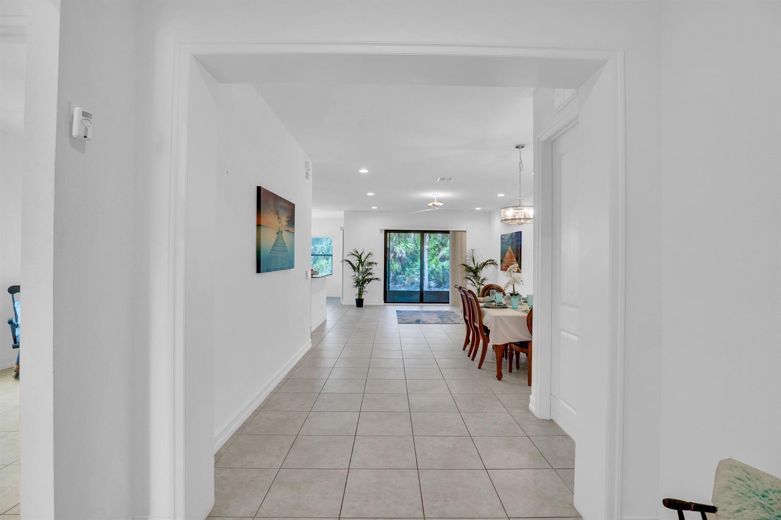 A view through a doorway into a dining area with tile floors and sliding doors — 5585 40th Avenue, Vero Beach FL 32967, VERO BEACH, FL