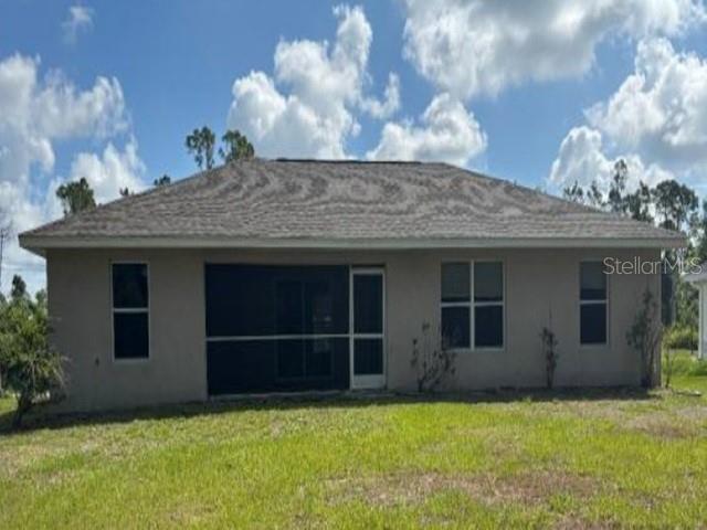 The rear exterior of a single-story house features a screened-in porch and a grassy yard — 5533 DOUGLAS ROAD, NORTH PORT, FL