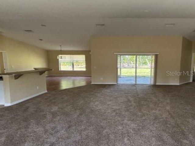 A spacious living area features beige walls, carpeted flooring, and a sliding glass door — 5533 DOUGLAS ROAD, NORTH PORT, FL