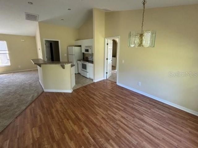 An open-concept kitchen features a breakfast bar, white appliances, and wood-look flooring — 5533 DOUGLAS ROAD, NORTH PORT, FL