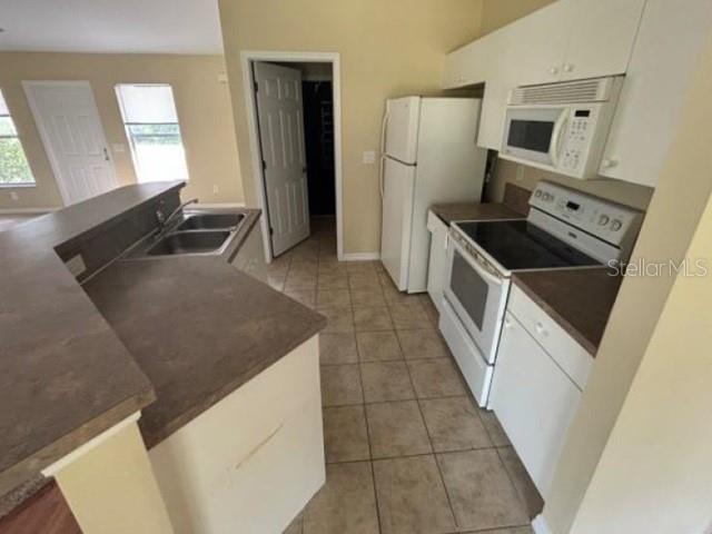 A kitchen features white appliances, light-colored cabinets, a tiled floor, and a breakfast bar — 5533 DOUGLAS ROAD, NORTH PORT, FL