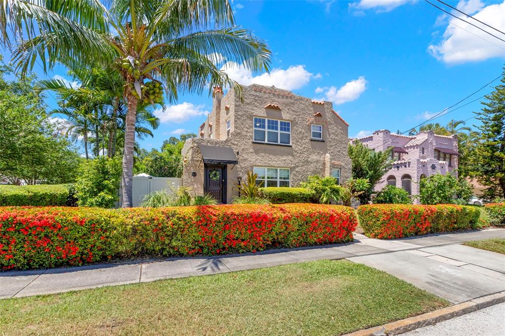 A two-story stucco house with a palm tree and a vibrant red hedge in front — 1125 11TH AVENUE N, ST PETERSBURG, FL