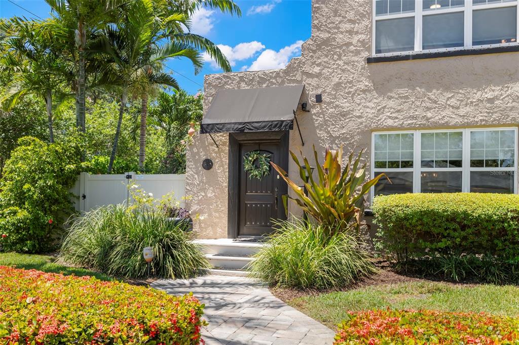A stucco house exterior features a dark front door with an awning and landscaping — 1125 11TH AVENUE N, ST PETERSBURG, FL