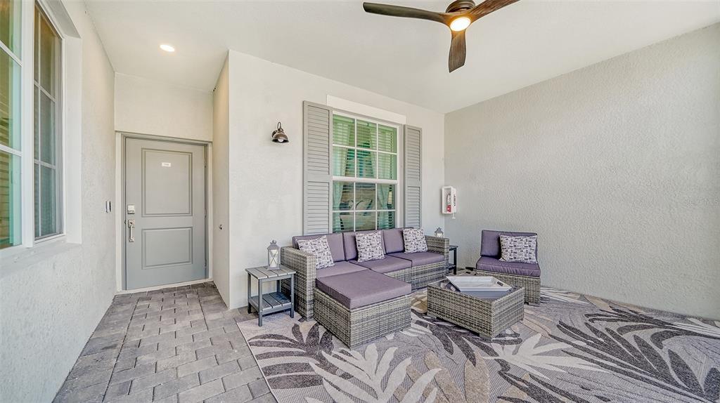 A covered patio features gray wicker furniture, a patterned rug, and a ceiling fan — 12550 GALAPAGOS COURT UNIT 106, VENICE, FL