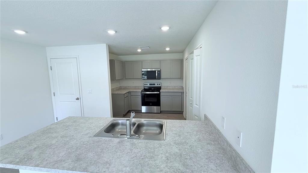 A kitchen features gray cabinets, stainless steel appliances, and a double-basin sink on the island — 54 PRINCETON LANE, PALM COAST, FL