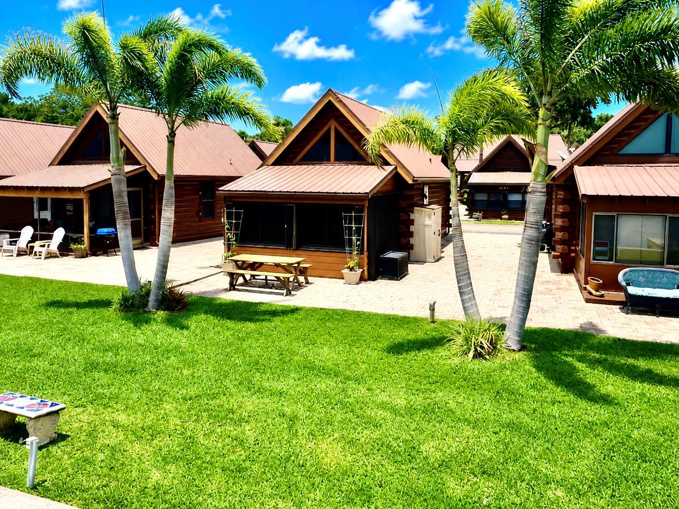 Several wooden cabins with metal roofs sit on a paved patio beside a green lawn — 8346 Us-441 # 10, Okeechobee FL 34974, OKEECHOBEE, FL
