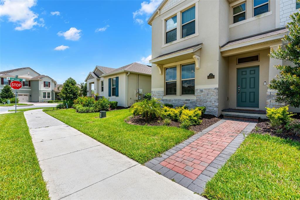 A two-story suburban house features a brick walkway leading to a teal front door — 15741 FOUNTAIN SPRINGS ROAD, WINTER GARDEN, FL