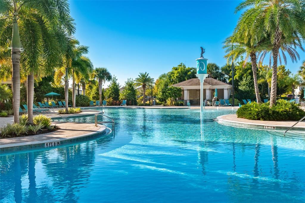 A resort-style swimming pool features palm trees, a central fountain, and lounge chairs — 15741 FOUNTAIN SPRINGS ROAD, WINTER GARDEN, FL