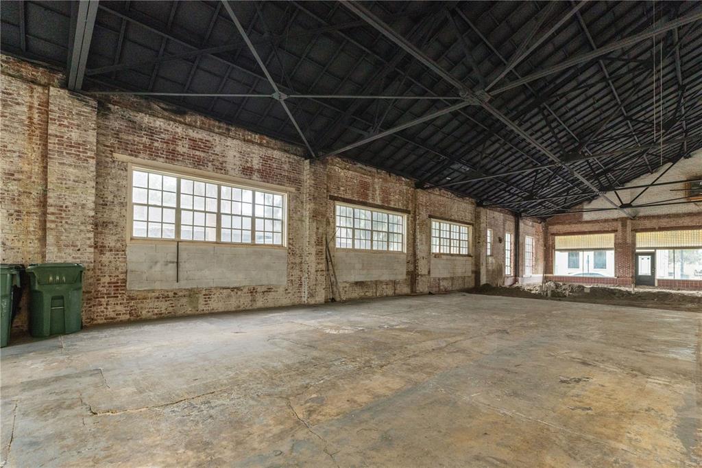 An empty industrial warehouse space with exposed brick walls, concrete floors, and a dark ceiling — 113 N 7TH STREET, LEESBURG, FL