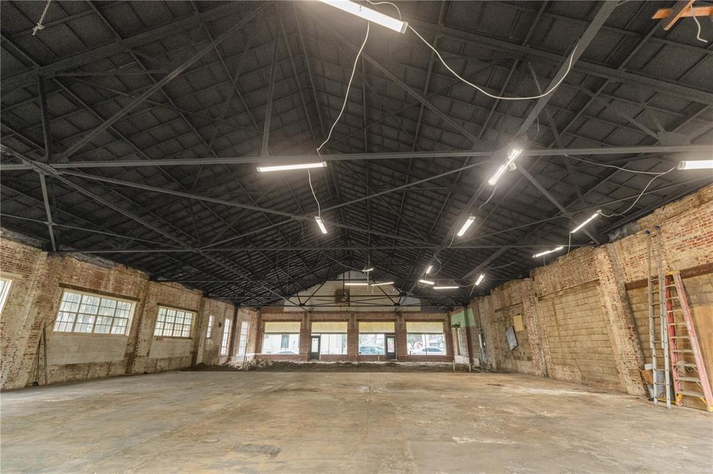 An expansive, open-concept industrial space features exposed brick walls, a high truss ceiling, and concrete floors — 113 N 7TH STREET, LEESBURG, FL