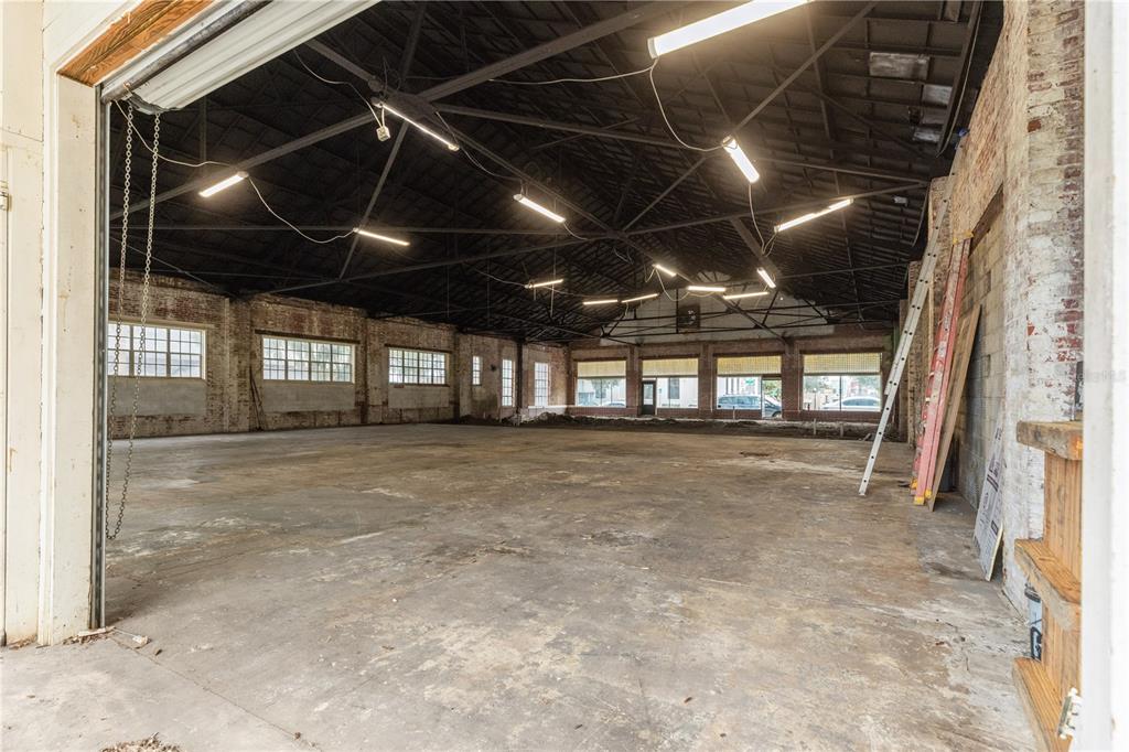An expansive, empty industrial warehouse space features exposed brick walls, concrete floors, and vaulted ceilings — 113 N 7TH STREET, LEESBURG, FL