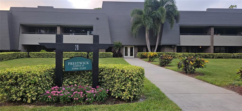 A multi-story building with a sign for Prestwick Lodge 20 stands behind a landscaped lawn — 36750 US HIGHWAY 19 N, PALM HARBOR, FL
