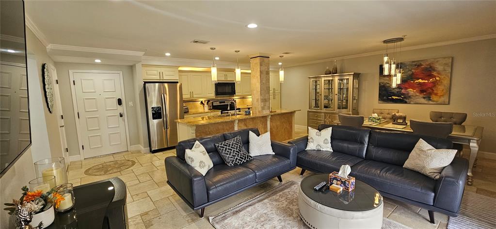 An open-concept living and dining area features a kitchen with stone counters and tile flooring — 36750 US HIGHWAY 19 N, PALM HARBOR, FL