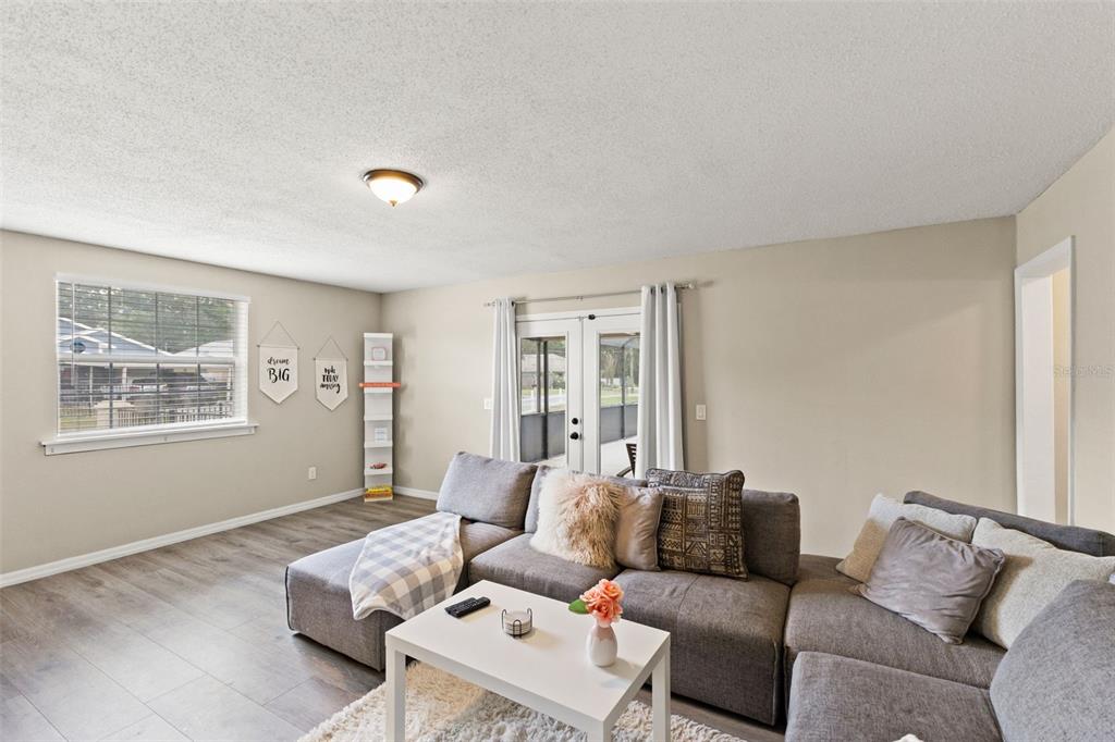 A living room features a grey sectional sofa, a white coffee table, and glass doors — 7901 N PACKWOOD AVENUE, TAMPA, FL