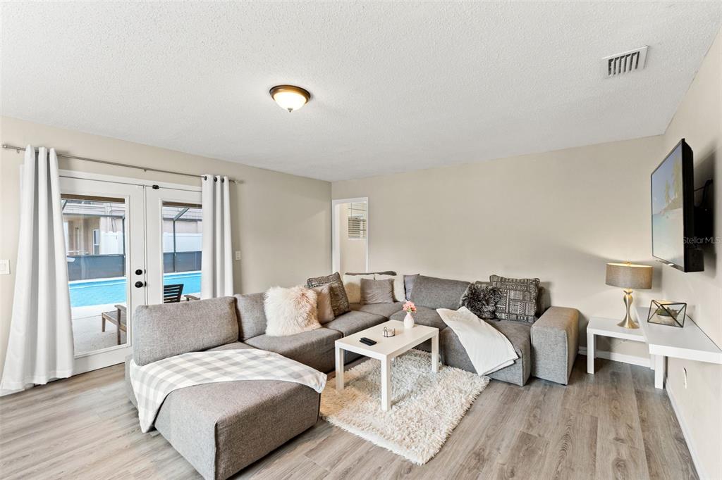 A living room features a gray sectional sofa, a white coffee table, and sliding glass doors — 7901 N PACKWOOD AVENUE, TAMPA, FL