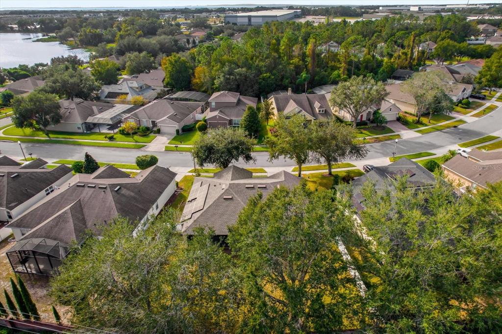 An aerial view shows a suburban neighborhood with houses, green trees, and a nearby lake — 2284 PICKFORD CIRCLE, APOPKA, FL