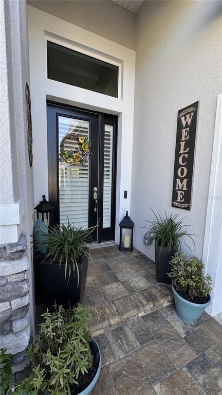 A front entryway features a black door with sidelights, potted plants, and a welcome sign — 20 SPRING STREET, PALM COAST, FL