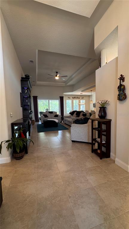 A living room features tile flooring, a tray ceiling with a fan, and neutral furniture — 20 SPRING STREET, PALM COAST, FL