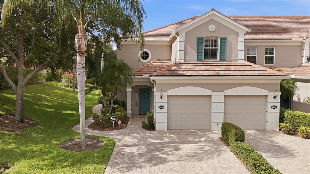 A two-story townhouse with a paved driveway, two garage doors, and a teal front door — 5290 DESCANSO COURT UNIT 201B19, SARASOTA, FL