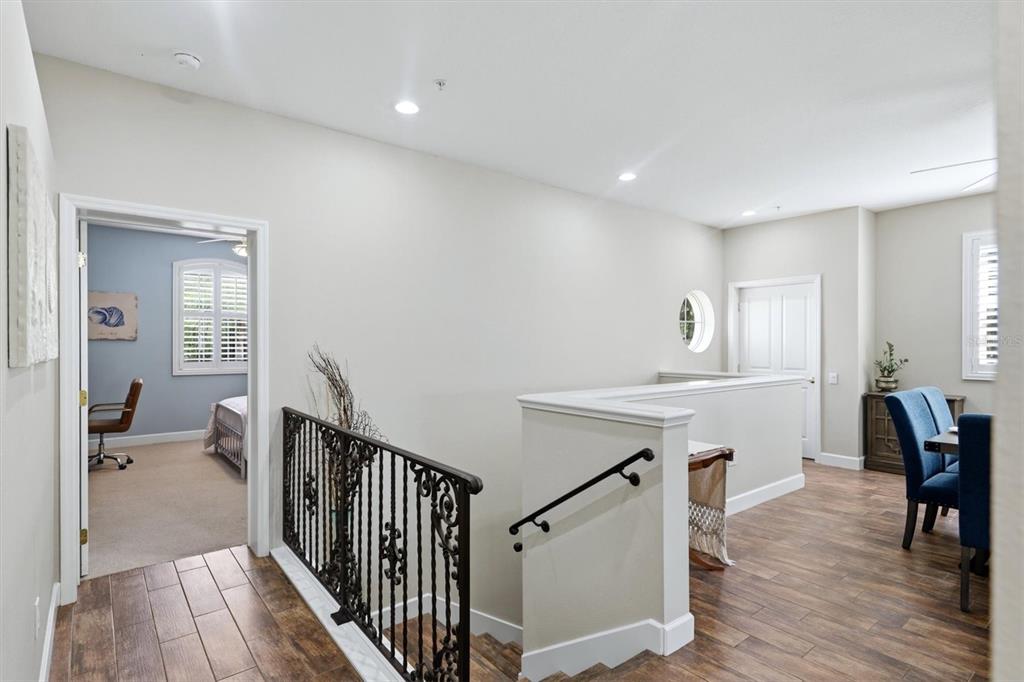 A landing area features wood-look tile flooring, a wrought-iron railing, and a view into a bedroom — 5290 DESCANSO COURT UNIT 201B19, SARASOTA, FL
