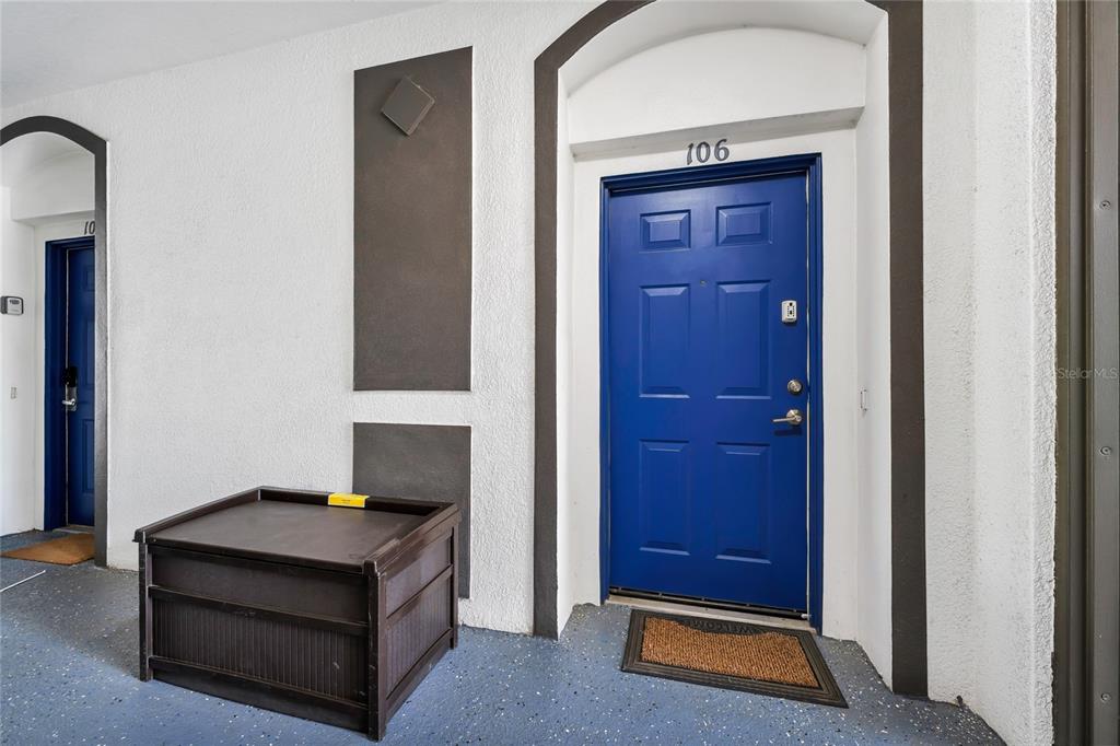 A blue front door labeled 106 sits next to a dark storage bin on a patio — 4114 BREAKVIEW DR DRIVE UNIT 10602, ORLANDO, FL