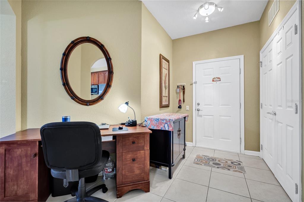 A home office area features a wooden desk, a black chair, and a round mirror — 4114 BREAKVIEW DR DRIVE UNIT 10602, ORLANDO, FL