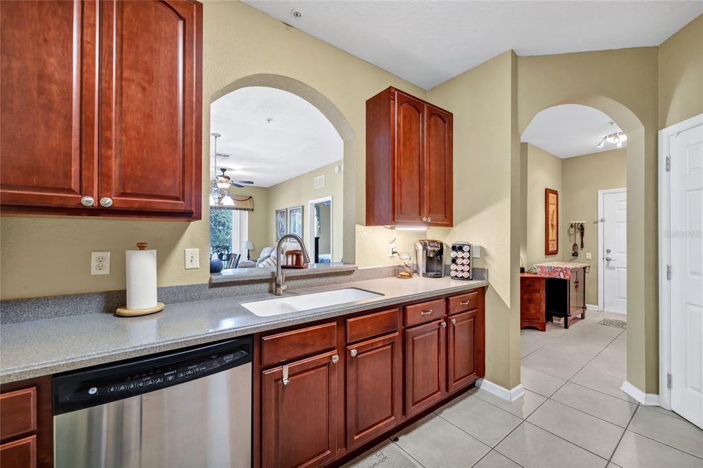 A kitchen features dark wood cabinets, gray countertops, a stainless steel dishwasher, and arched openings — 4114 BREAKVIEW DR DRIVE UNIT 10602, ORLANDO, FL