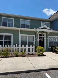 A two-story green townhouse with a white picket fence and a concrete walkway — 2212 SAN VITTORINO CIRCLE UNIT 103, KISSIMMEE, FL