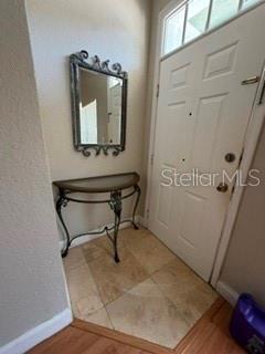 An entryway features a semi-circular metal console table, a wall mirror, and tiled flooring — 2212 SAN VITTORINO CIRCLE UNIT 103, KISSIMMEE, FL