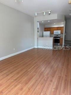An open-concept living area features wood-look flooring and a view into the kitchen — 2212 SAN VITTORINO CIRCLE UNIT 103, KISSIMMEE, FL