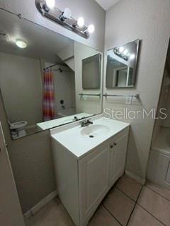 A bathroom features a white vanity, a large wall mirror, and a shower with a curtain — 2212 SAN VITTORINO CIRCLE UNIT 103, KISSIMMEE, FL