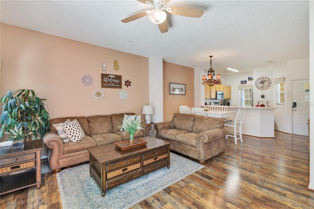 A living room with brown sofas, a wooden coffee table, and an adjacent dining area — 8456 CRYSTAL COVE LOOP, KISSIMMEE, FL