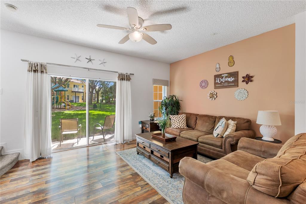A living room features brown sofas, a wooden coffee table, and a sliding glass door — 8456 CRYSTAL COVE LOOP, KISSIMMEE, FL