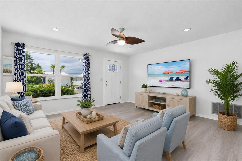 A living room features light wood flooring, a ceiling fan, a television, and blue furniture — 3715 98TH AVENUE N UNIT 3, PINELLAS PARK, FL