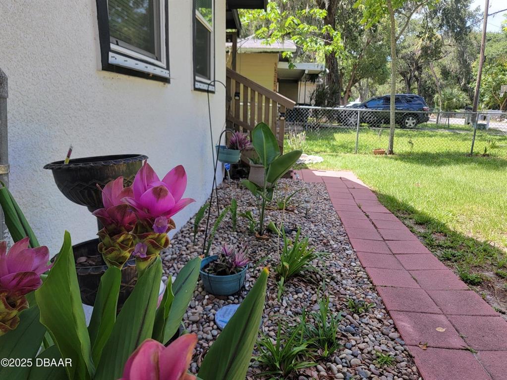 A side yard features a stone path, a garden bed with pink flowers, and landscaping — 620 WASHINGTON STREET, DAYTONA BEACH, FL