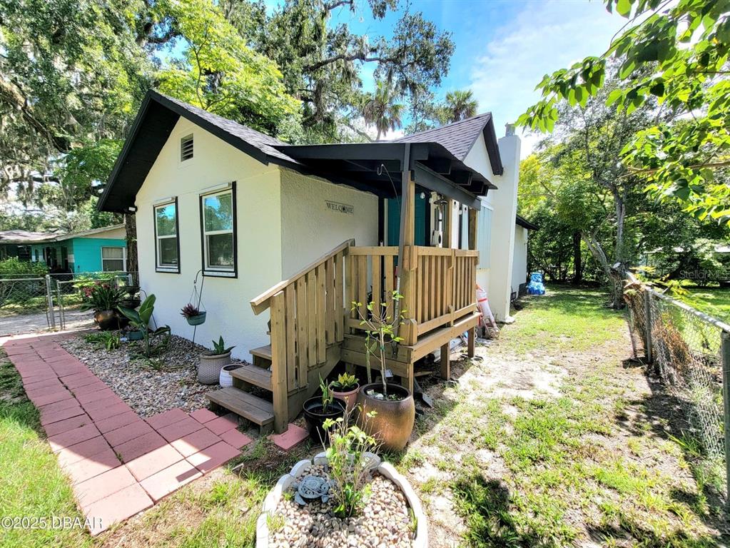 A white house with a wooden porch and stairs sits on a gravel and grass lot — 620 WASHINGTON STREET, DAYTONA BEACH, FL