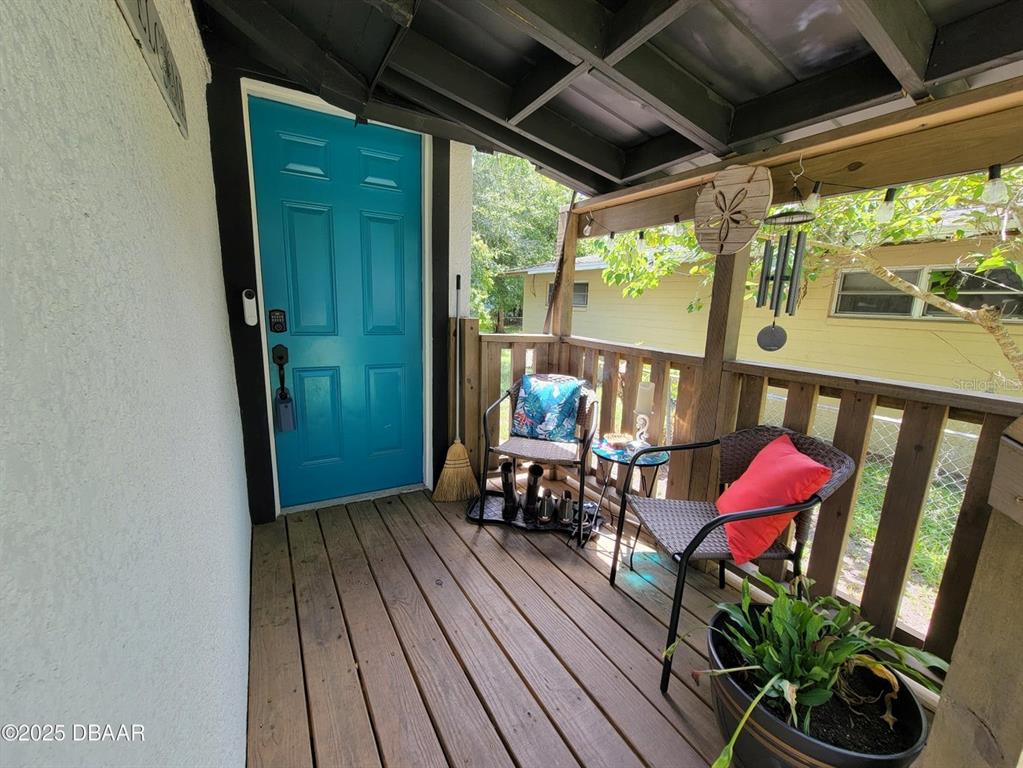 A covered wooden porch features a bright blue front door, two chairs, and a potted plant — 620 WASHINGTON STREET, DAYTONA BEACH, FL