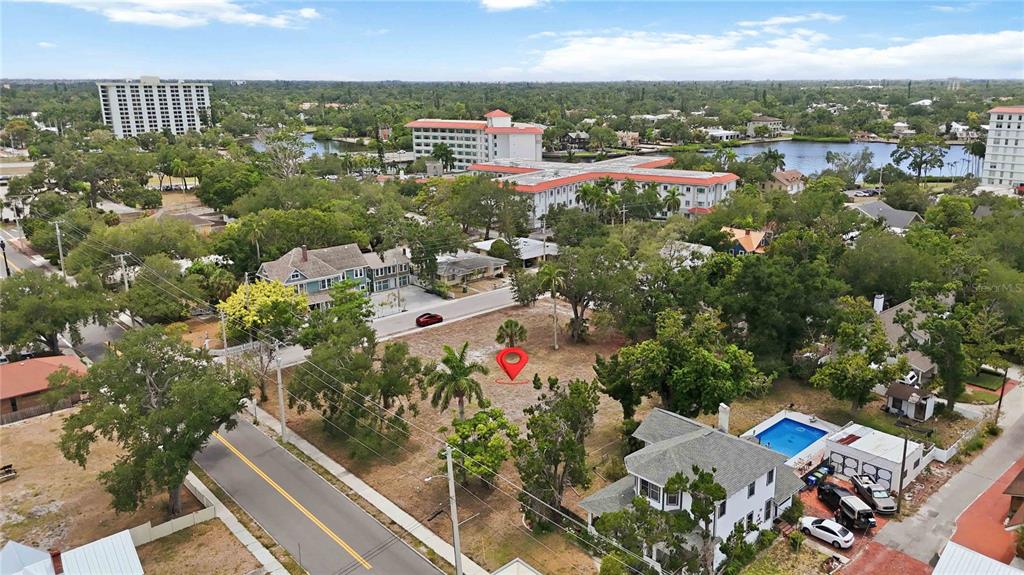 An aerial view shows a vacant, tree-lined lot marked with a red pin in a neighborhood — 204 15TH STREET W, BRADENTON, FL