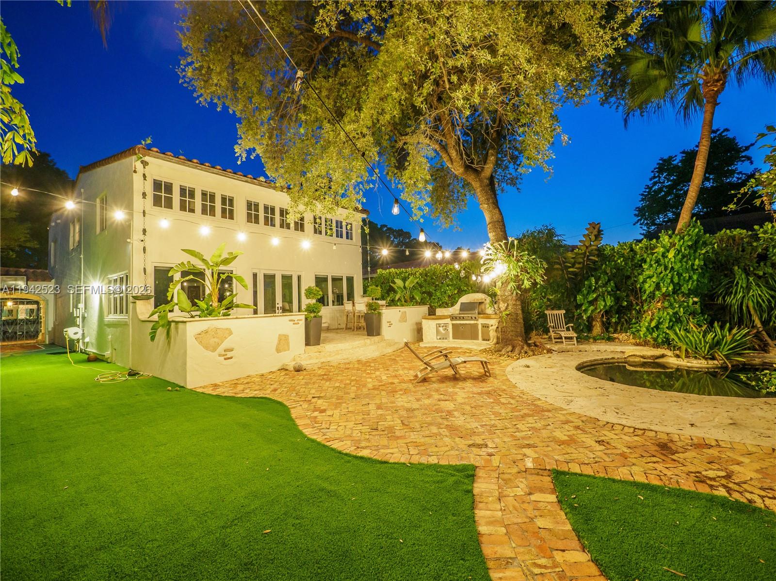 A backyard features a white house, brick patio, artificial turf, and a small pool — 1229 Sorolla Ave, Coral Gables FL 33134, CORAL GABLES, FL
