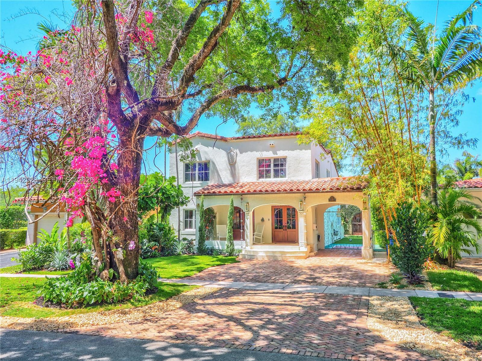 A two-story Mediterranean-style house with a brick driveway, arched porch, and a large flowering tree — 1229 Sorolla Ave, Coral Gables FL 33134, CORAL GABLES, FL
