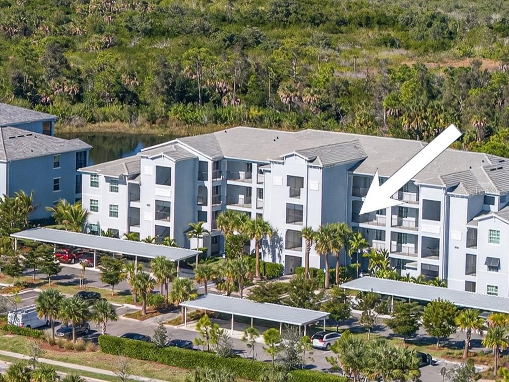 An aerial view of a multi-story apartment building with covered parking and surrounding landscaping — 14141 HERITAGE LANDING BOULEVARD UNIT 934, PUNTA GORDA, FL
